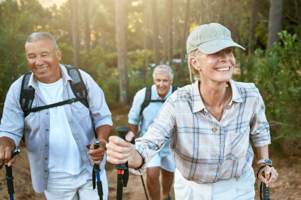 Hiking retired, elderly and senior friends or tourists in forest or mountains for fitness, health a